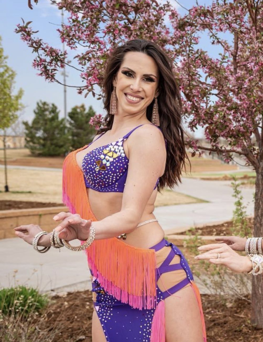 Joyful woman showcasing her belly dance prowess in Denver's premier belly dance classes